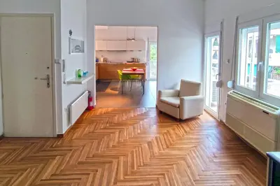 a living room with a hard wood floor and a chair at Sunny southern Athens flat near the seaside in Athens