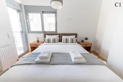 a large white bed in a white bedroom with windows at Waylink Residences - Marina Floisvou in Athens