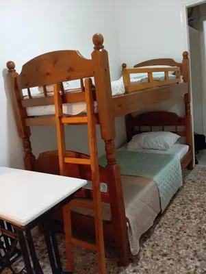 two bunk beds in a room with a table at Wooden bunk bed in a dorm 5' from metro in Athens