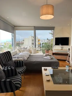 a living room with a couch and a large window at Top roof luxury studio near metro! in Athens