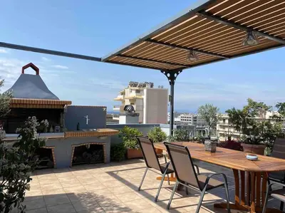 a patio with a wooden table and chairs and a fireplace at Top roof luxury studio near metro! in Athens