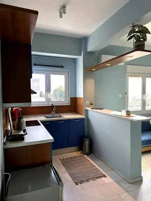 a kitchen with blue walls and a sink and a counter at Flat by the Beach Voula in Athens