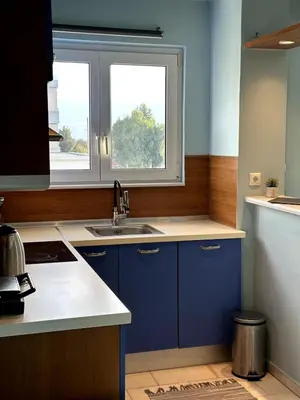 a kitchen with blue cabinets and a sink and a window at Flat by the Beach Voula in Athens