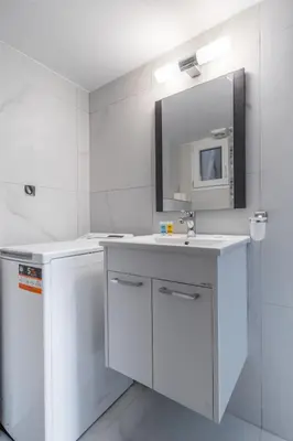 a white bathroom with a sink and a mirror at Flat by the Beach Voula in Athens