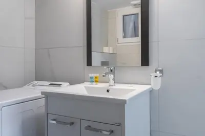 a white bathroom with a sink and a mirror at Flat by the Beach Voula in Athens