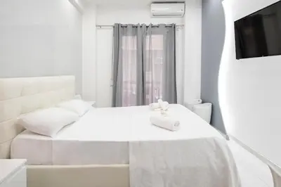 a white bedroom with a bed and a television at Estia in Athens