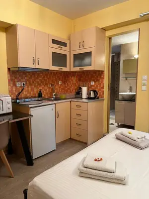 a small kitchen with white appliances and a table at Cozy ground floor studio near metro! in Athens