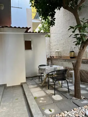 a patio with a bench and a table and a tree at Cozy ground floor studio near metro! in Athens