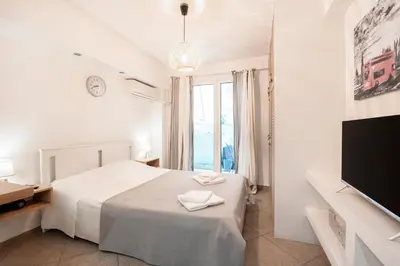 a white bedroom with a bed and a television at Ifigenia in Athens