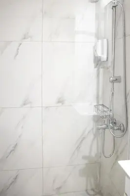 a bathroom with a shower with white marble walls at Ifigenia in Athens