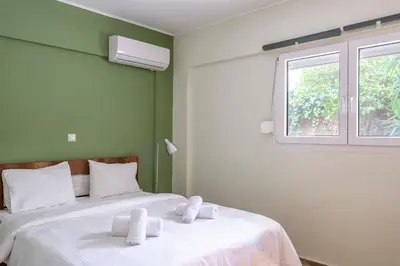 a bedroom with two beds with white sheets and a window at Dousma Apartment in Athens