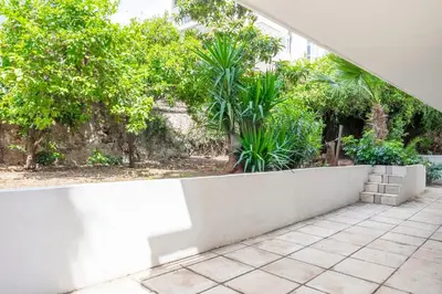 a white concrete wall with trees in the background at Dousma Apartment in Athens