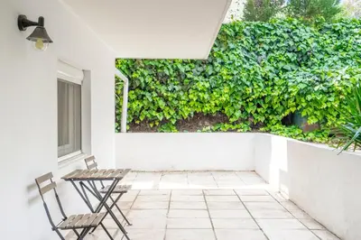 a patio with two chairs and a green hedge at Dousma Apartment in Athens