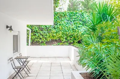 a patio with two chairs and a green wall at Dousma Apartment in Athens
