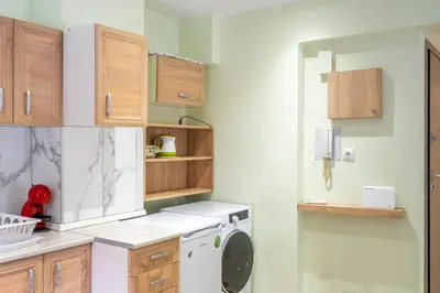 a washing machine in a kitchen with wooden cabinets at Dousma Apartment in Athens