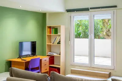 a living room with a tv and a desk and a window at Dousma Apartment in Athens