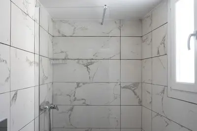 a bathroom with white marble walls and a shower at Andre Apartment in Athens