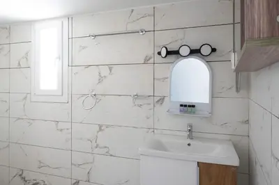 a white tiled bathroom with a sink and a mirror at Andre Apartment in Athens