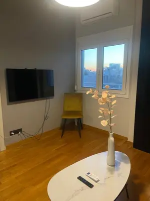 a living room with a table and a television and a vase with flowers at Exarcheia Athens Penthouse in Athens
