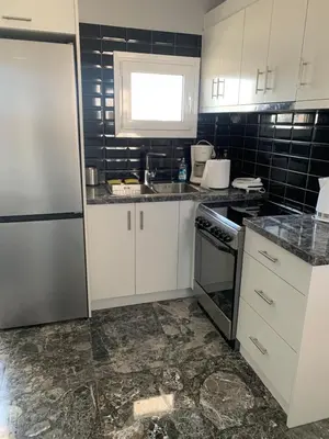 a kitchen with white cabinets and a black tile wall at Exarcheia Athens Penthouse in Athens