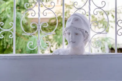 a statue of a bust in front of a fence at White & Stars in Athens