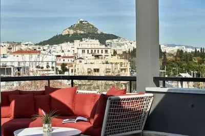 a couch on a balcony with a view of a city at AthensWas Design Hotel in Athens