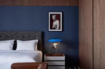 a bedroom with a blue wall with a bed and a lamp at AthensWas Design Hotel in Athens