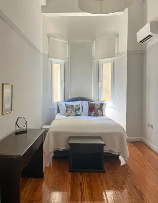 a bedroom with a bed with a table and two windows at Athens Center, Akadimias 77 - 1rst floor in Athens