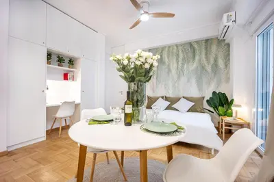 a white living room with a table and a couch at Palm Athens by GK Properties in Athens