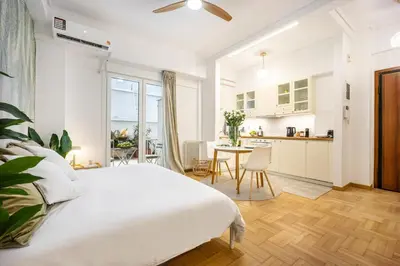 a white bedroom with a large bed and a kitchen at Palm Athens by GK Properties in Athens