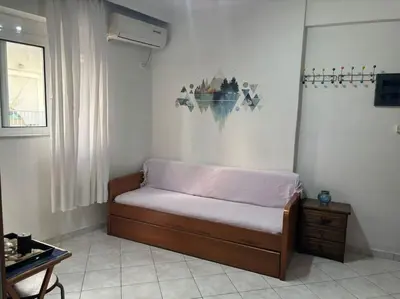 a small bed in a room with a table at Thissio Gazi apartment with private parking in Athens