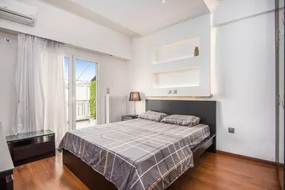 a bedroom with a bed and a large window at Modern spacious apt in Athens in Athens