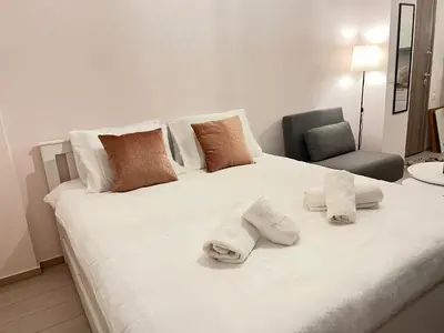 a white bed with towels on it with a chair at Alice Museum Retreat in Athens