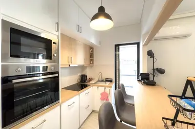 a kitchen with white cabinets and a black oven at Maya's Apt near Athens center in Athens