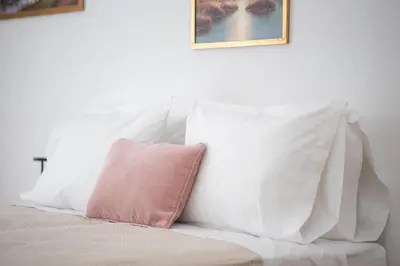 a white bed with a pink pillow on it at Eclectic Moonstone apartment in Athens in Athens