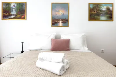 a bedroom with a bed with three paintings on the wall at Eclectic Moonstone apartment in Athens in Athens