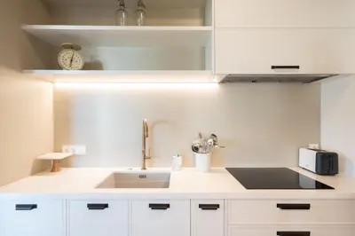 a kitchen with white cabinets and a sink and a clock at Luxury Petralona Penthouse - Sleeps 7 -Near Metro in Athens