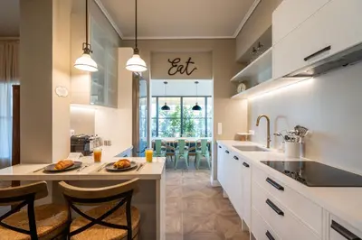 a kitchen with white cabinets and a dining room at Luxury Petralona Penthouse - Sleeps 7 -Near Metro in Athens