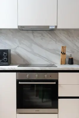 a kitchen with a black oven and white cabinets at Cozy & Chic Stay with Patio Near Metro Station in Athens