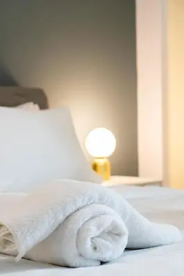 a white towel on a bed next to a lamp at Chic One-Bedroom retreat near Panathenaic Stadium in Athens