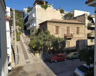 an old building with cars parked in a parking lot at Charming Stone house, 500 meters to Acropolis in Athens
