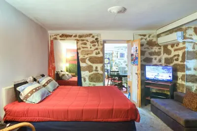 a bedroom with a bed and a living room with a tv at Charming Stone house, 500 meters to Acropolis in Athens