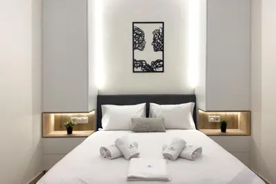 a bedroom with a white bed with three pillows at White Luxe Suite in Kolonaki in Athens