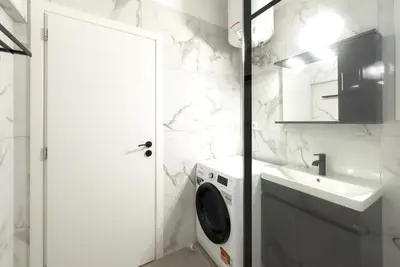 a bathroom with a washing machine and a sink at White Luxe Suite in Kolonaki in Athens