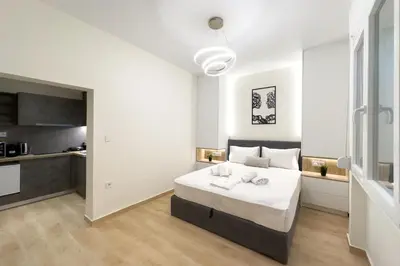 a white bedroom with a bed and a kitchen at White Luxe Suite in Kolonaki in Athens