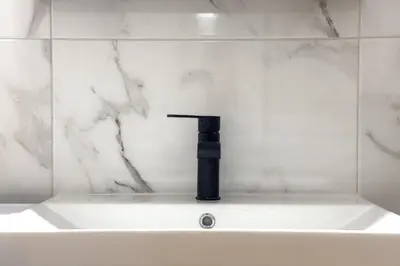 a white sink with a black faucet in a bathroom at White Luxe Suite in Kolonaki in Athens