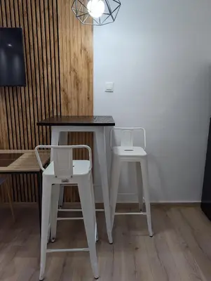 a table and two white chairs next to a tv at MatchBox 3siblings in Athens
