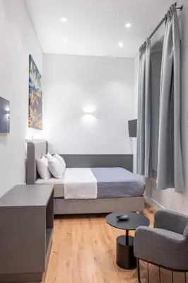 a small bedroom with a bed and a chair at Athinaidos rooms Prime location in Athens