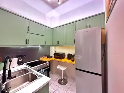 a kitchen with green cabinets and a sink and a refrigerator at St Tomas Square Apartment in Athens