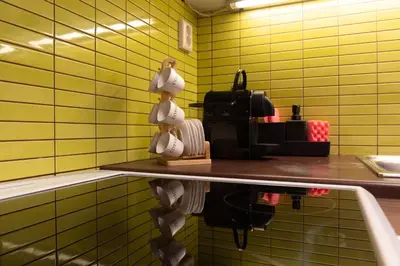 a kitchen with yellow tiled walls and a shelf with cups at athens guest in Athens